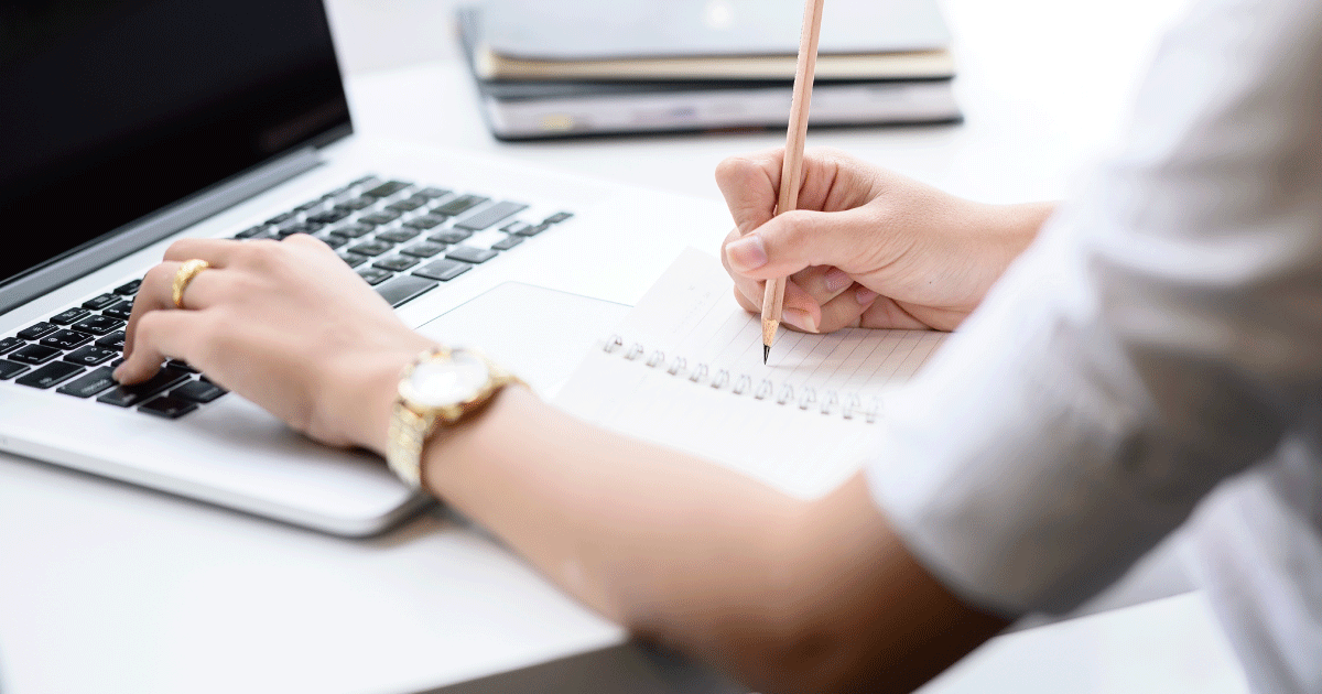 ノートに書きながらパソコンで作業し、考えを整理している様子